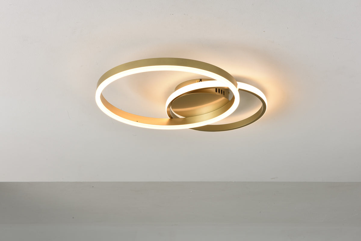 Plafondlamp Area brandend met warm licht langs de gouden ringen