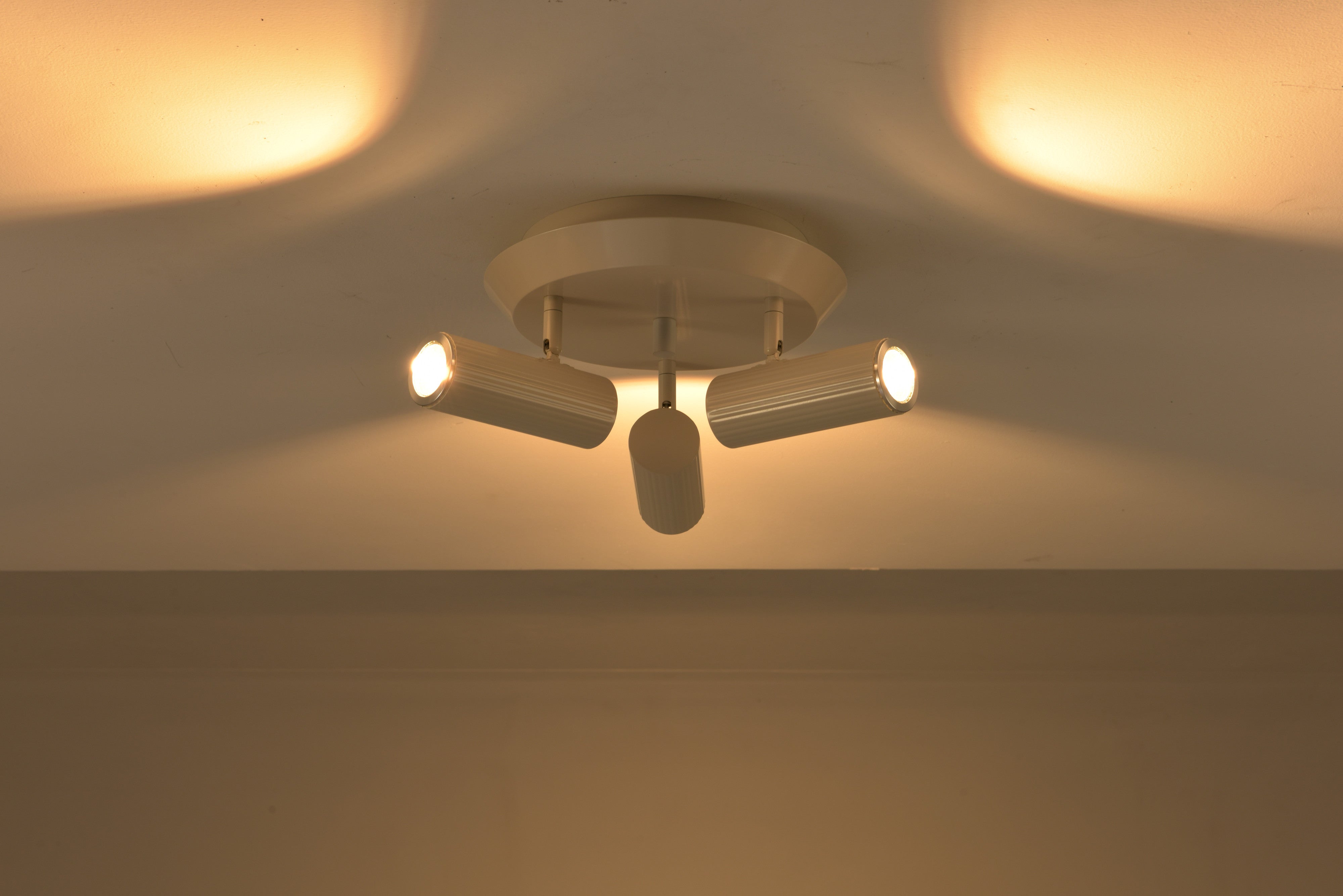 Plafondlamp Flush in beige brandend met warme lichtbundels op het plafond