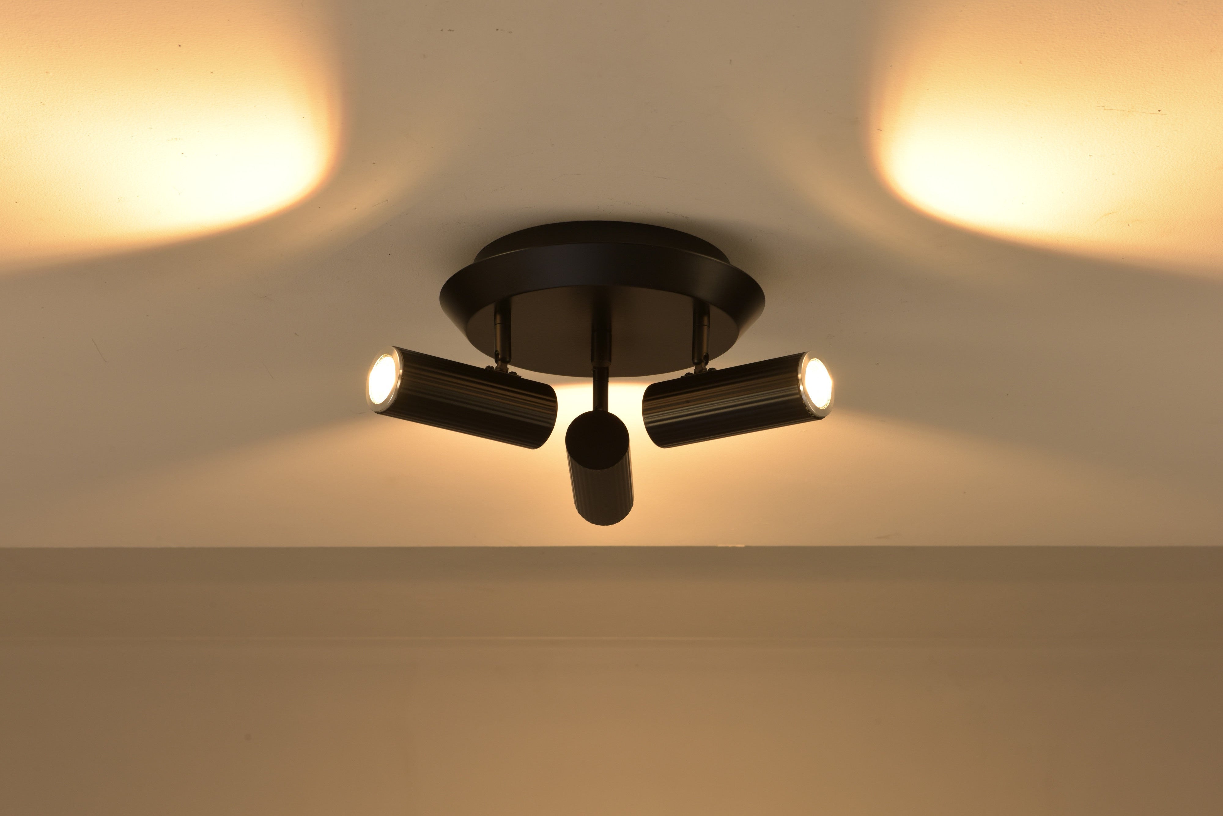 Plafondlamp Flush in zwart brandend met warme lichtbundels op het plafond