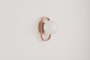 Wandlamp Jessica in brons met opaalwitte bol in een bronzen ring op een witte wand