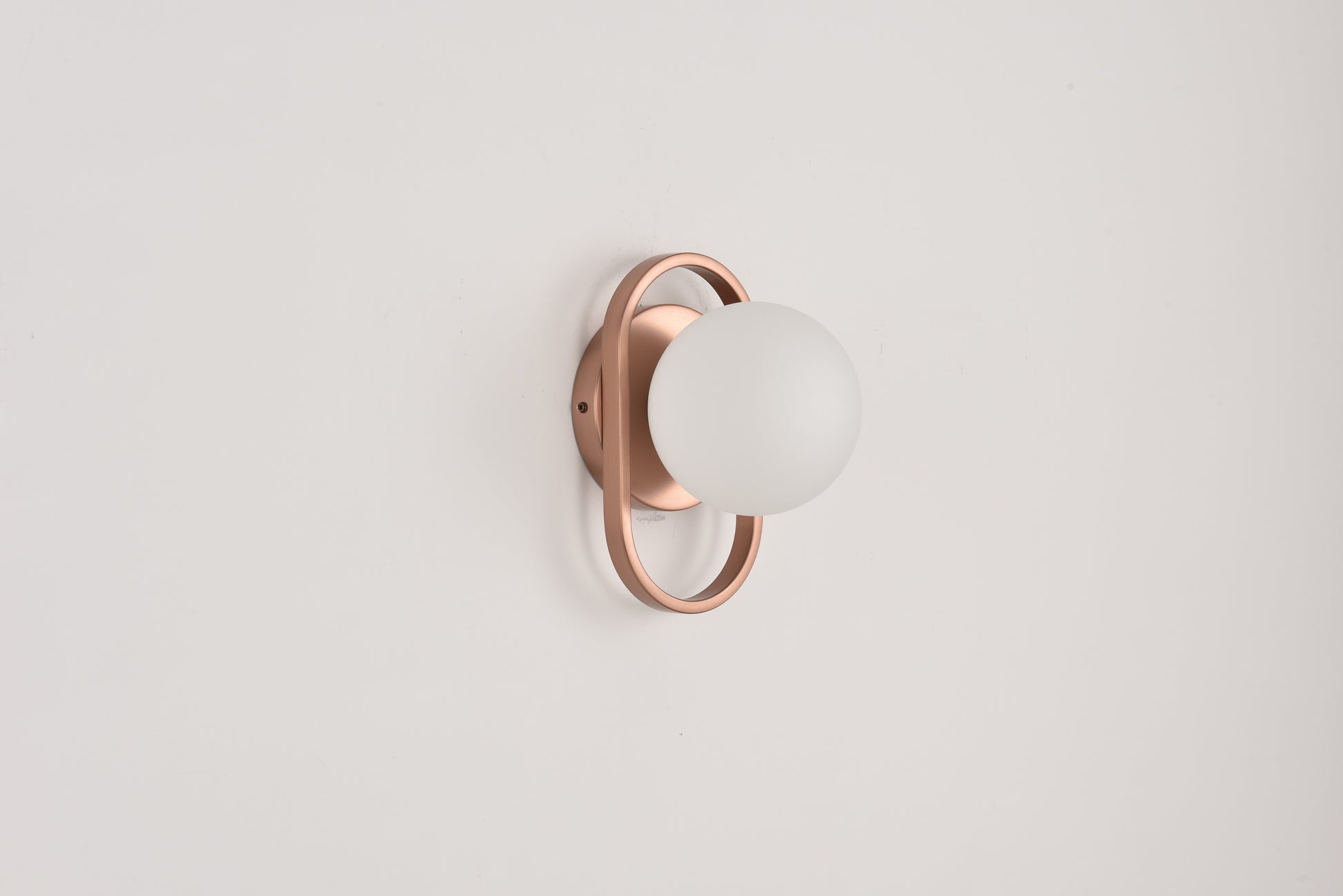 Wandlamp Jessica in brons met opaalwitte bol in een bronzen ring op een witte wand
