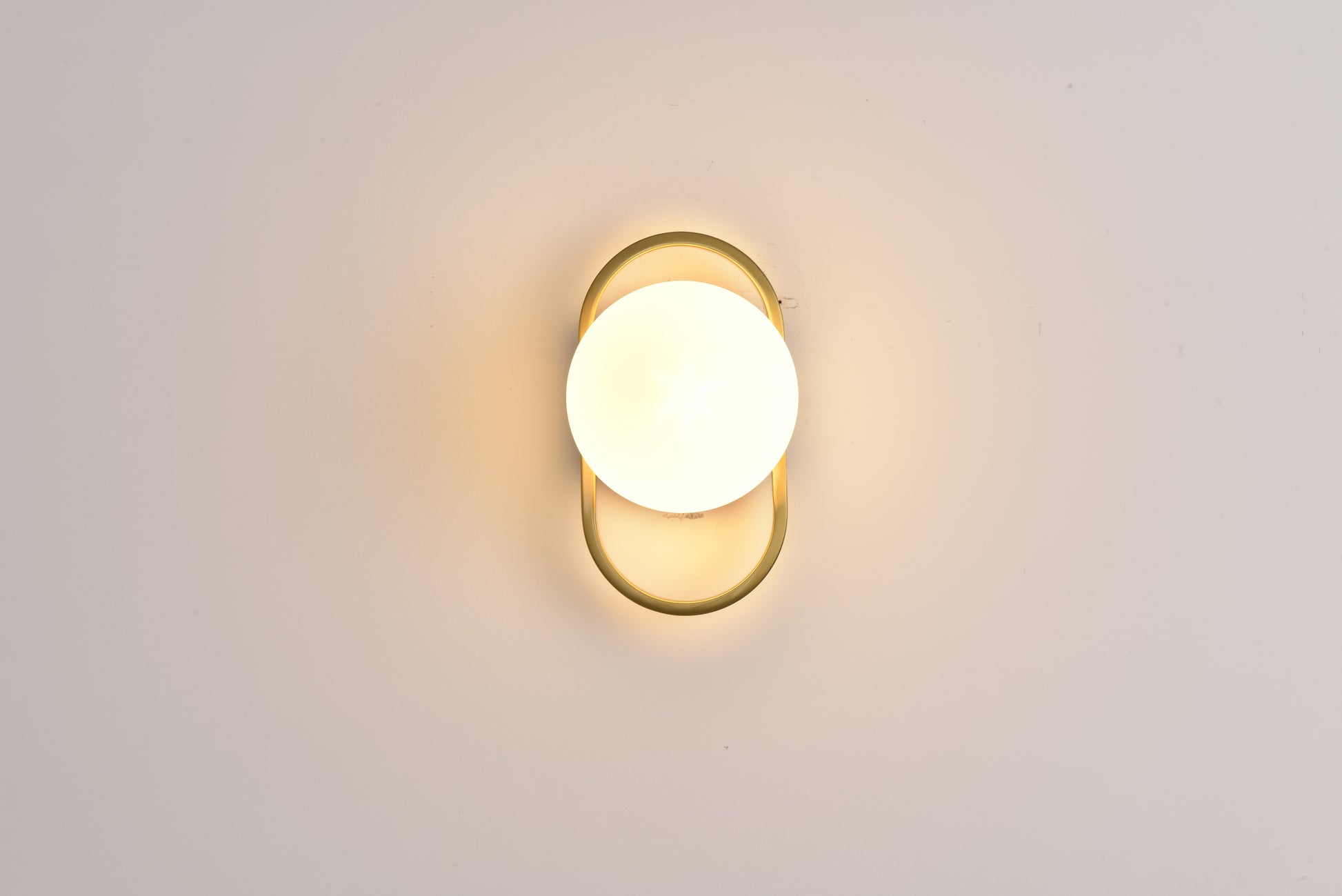Wandlamp Jessica in goud brandend recht van voren met warm licht rondom