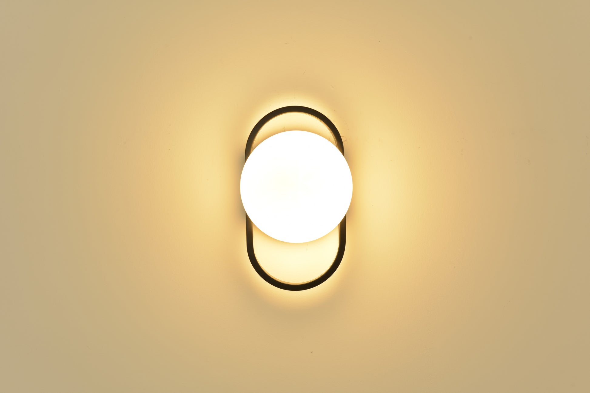 Wandlamp Jessica in zwart brandend recht van voren met warm licht rondom