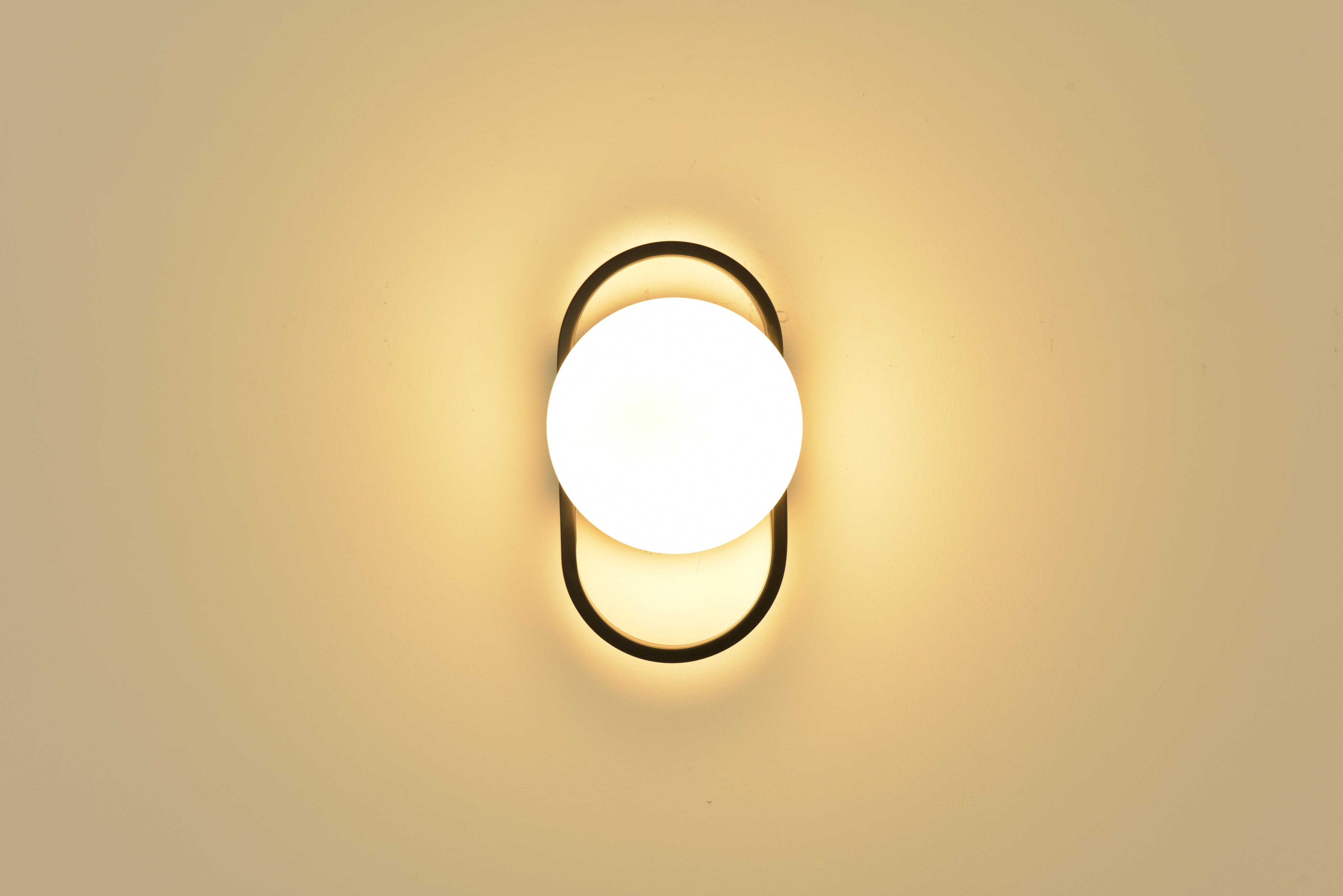 Wandlamp Jessica in zwart brandend recht van voren met warm licht rondom