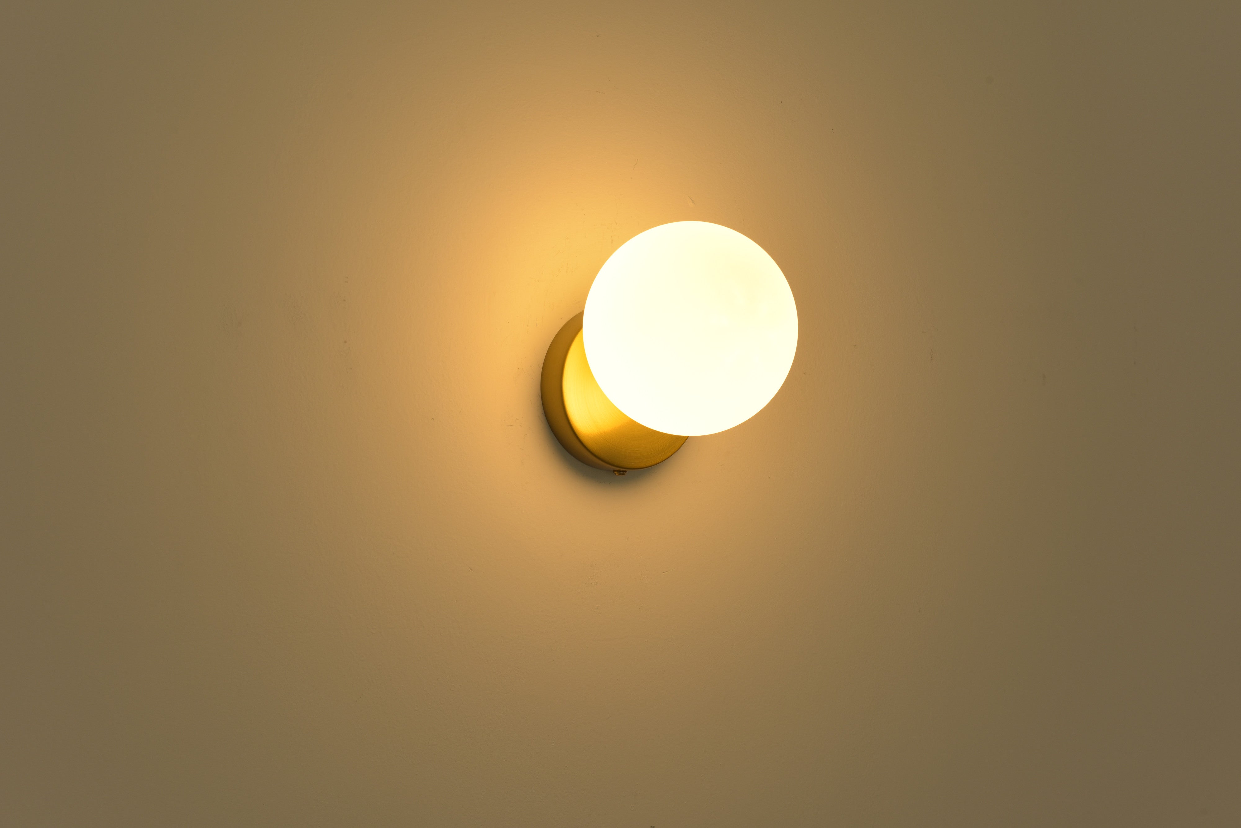 Wandlamp Maria in goud brandend met warme gloed op de wand