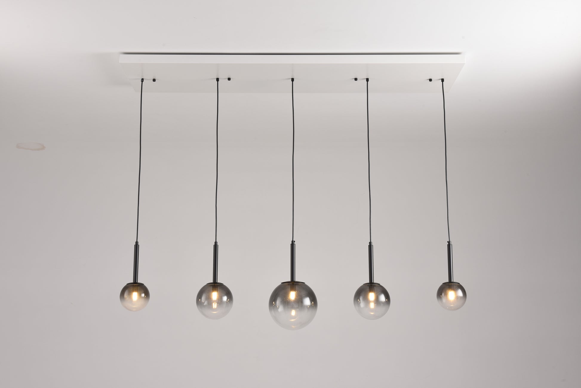 Hanglamp Stellar met vijf rookglazen bollen aan een witte balk