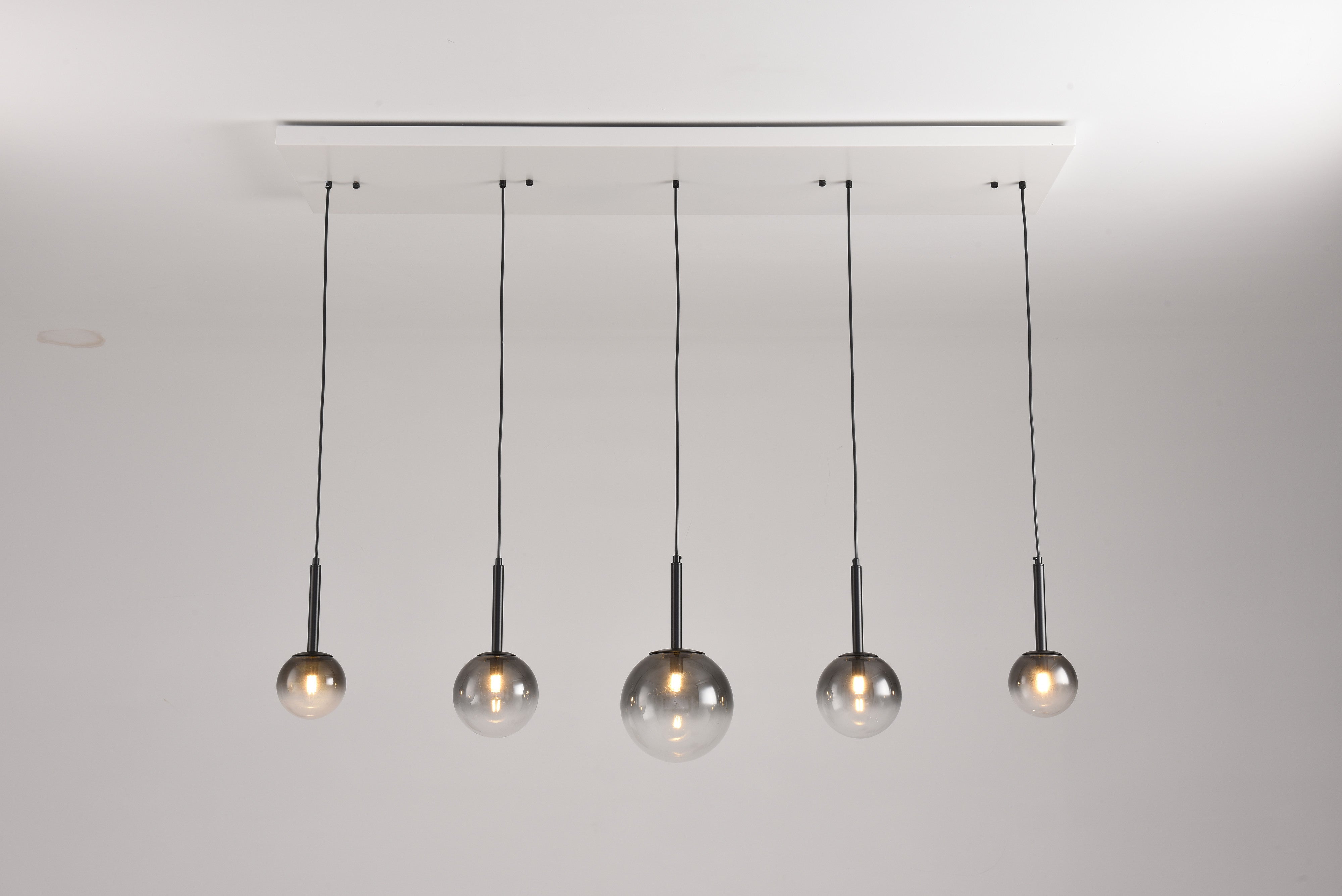 Hanglamp Stellar met vijf rookglazen bollen aan een witte balk