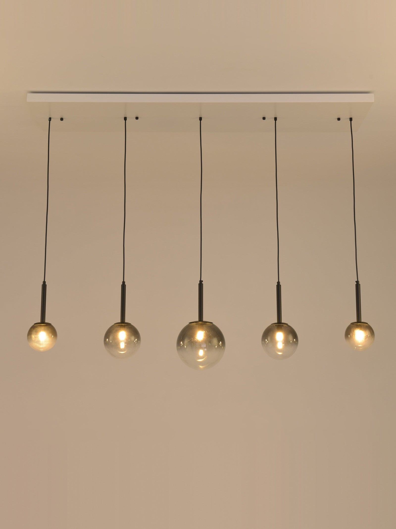 Hanglamp Stellar met brandende lampen, vijf rookglazen bollen op rij