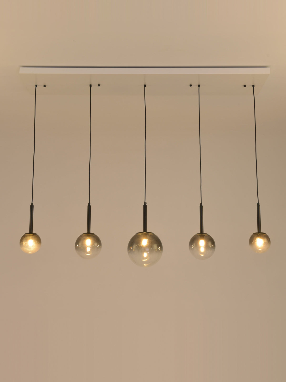 Hanglamp Stellar met brandende lampen, vijf rookglazen bollen op rij