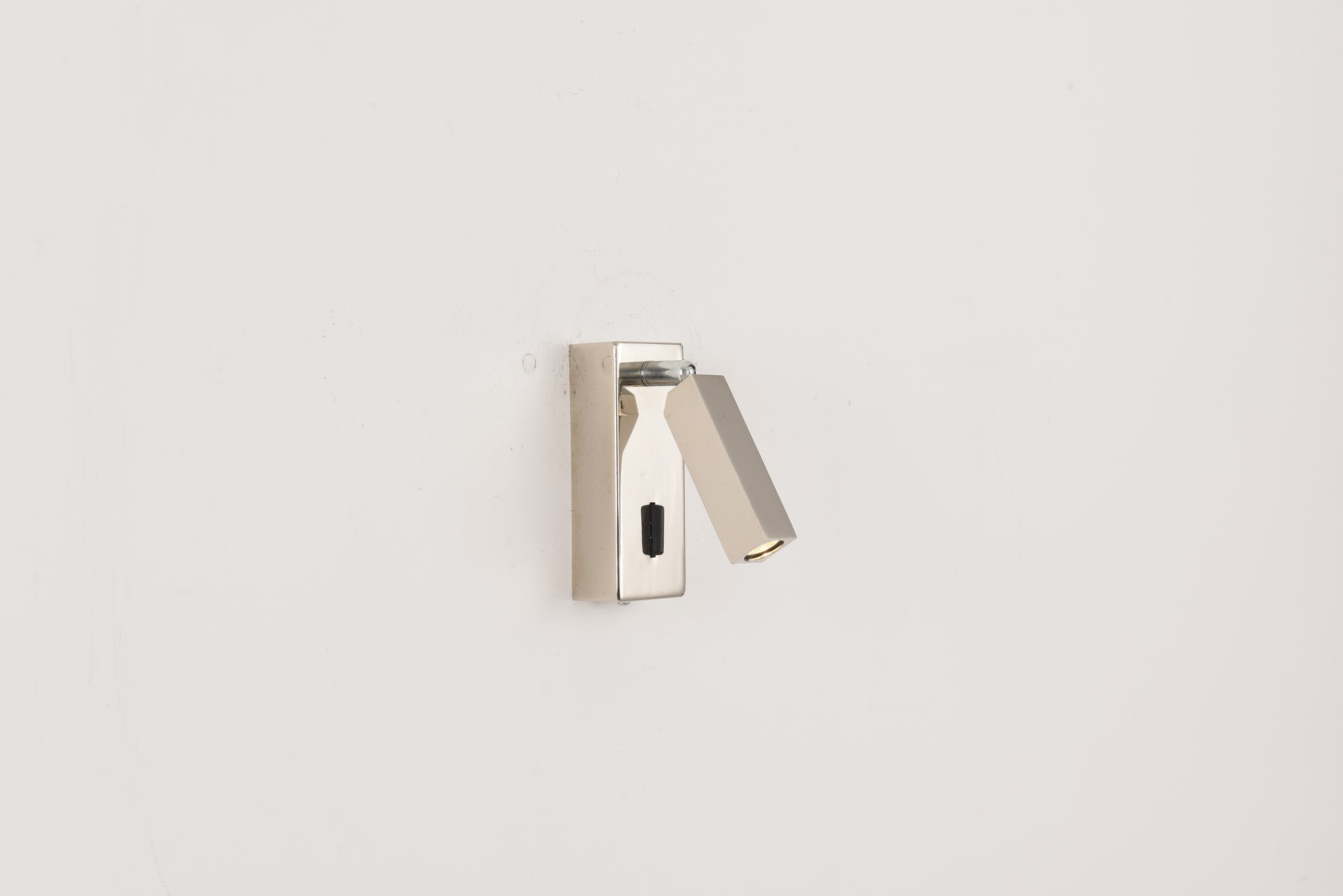 Wandlamp Vero in nikkel met uitgeklapte richtbare leespot tegen een witte wand