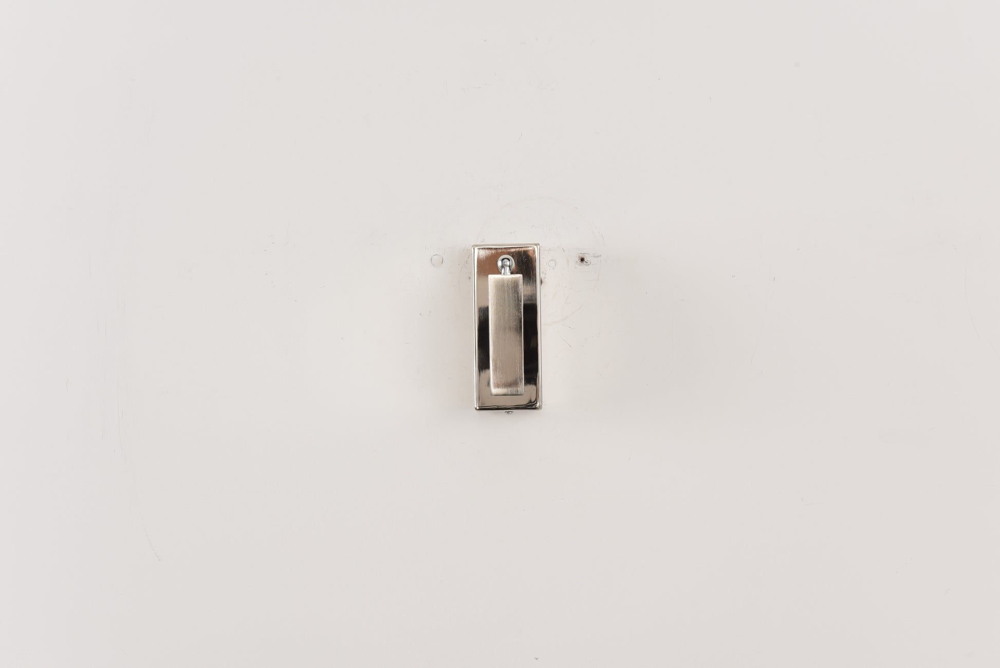 Wandlamp Vero in nikkel met de spot volledig ingeklapt tegen een witte wand