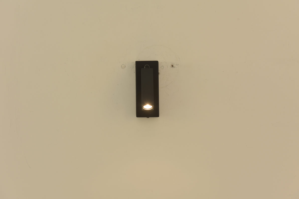 Wandlamp Vero in zwart met de spot ingeklapt en brandend in de behuizing
